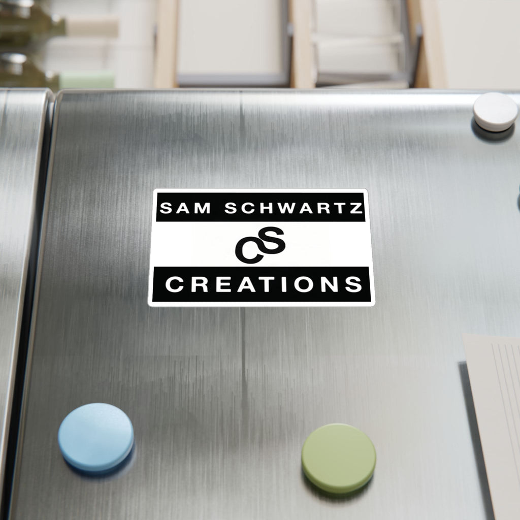 A rectangular white and black refrigerator magnet reading 'SAM SCHWARTZ CREATIONS' with a stylized logo, attached to a brushed stainless steel fridge door next to other magnets.